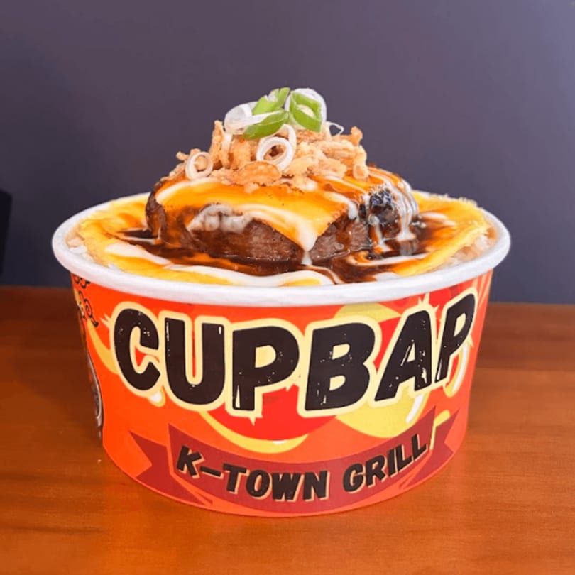 A Cupbap from K-Town Grill, featuring a burger patty, melted cheese, sauce, and scallions.